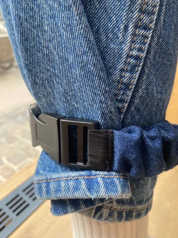Close-up of the buckle fastened over a rolled denim hem