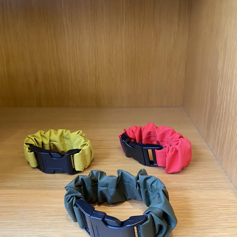 Mustard, Coral Red and Army Green straps on a wooden shelf